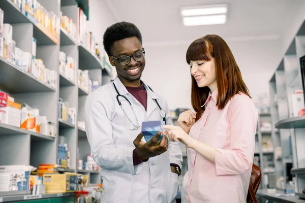 Kadın alıcı eczanede adam eczacıyla danışır