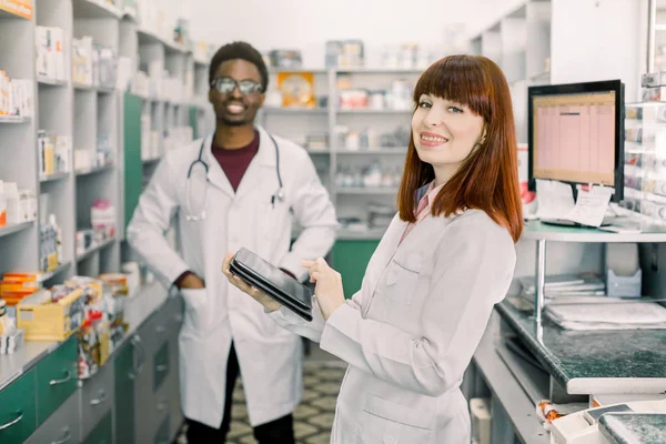 Portret wieloetnicznej farmakologów męskich i żeńskich, uśmiechniętych przed lekami w aptstore — Zdjęcie stockowe