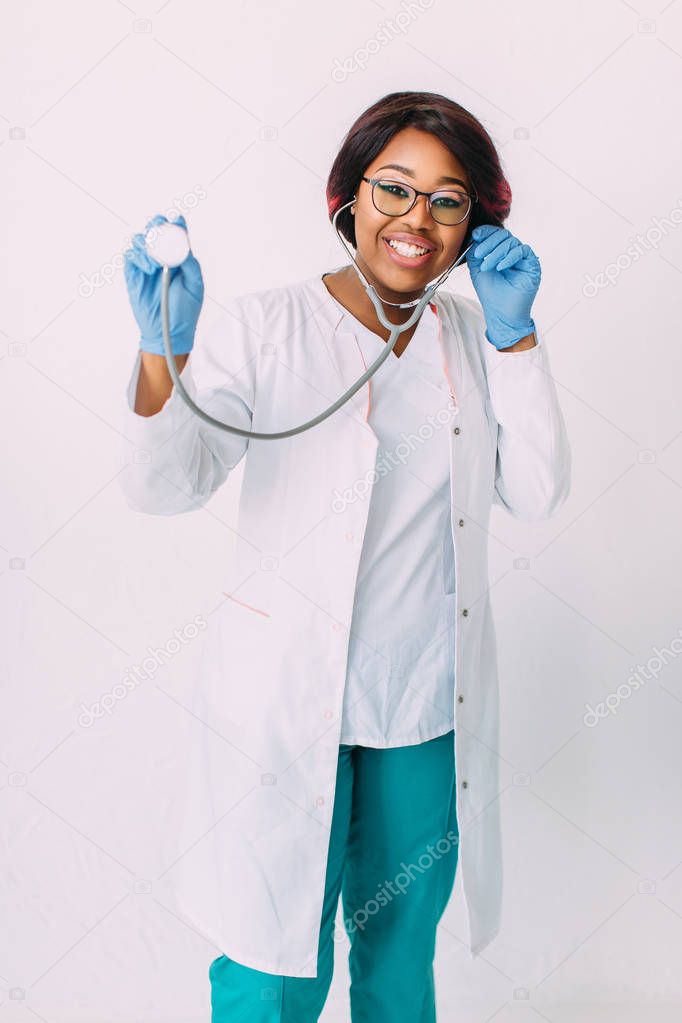 Young smiling African American woman doctor in white coat holding a stethoscope