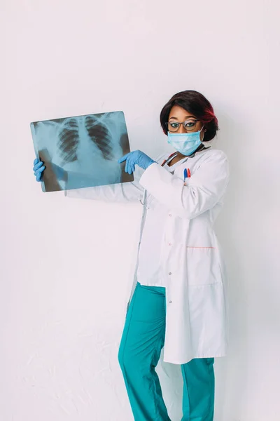 Молодий усміхнений Африканський американський лікар у медичній масці Холдинг пацієнти рентгенівської — стокове фото