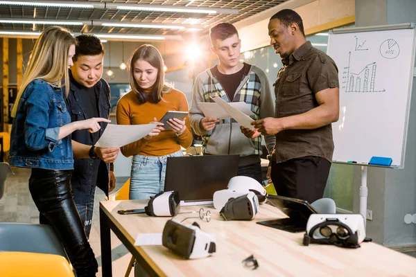 Üzleti csapat öt ember dolgozik együtt szerkentyű és papírok. Virtuális valóság szemüveg vagy szemüveg az asztalra. Modern irodai szoba, telekonferencia — Stock Fotó