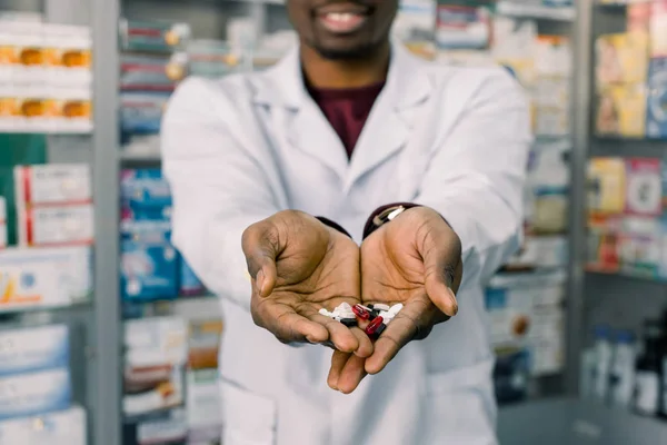 African-American farmaceuta mężczyzna trzyma Tabletki pigułki w rękach. Mans ręce trzymające garść pigułki medycyny, w leczeniu chorób — Zdjęcie stockowe