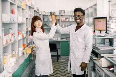 Eczanede kadın ve erkek eczacılar. Afrikalı erkek ve Kafkas kadın beş veren, modern eczanede çalışan