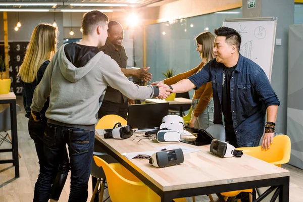 Team av utvecklare som arbetar med Virtual Reality-glasögon under ett affärsmöte. Unga affärskollegor brainstorming, handskakning vid mötet i moderna kontorsrum. — Stockfoto