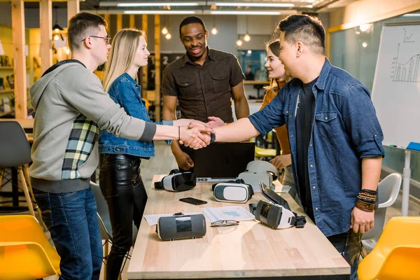 Csapat fejlesztők dolgozó virtuális valóság szemüveg során üzleti találkozón. Fiatal kollégák ötletbörze, kézremegés a modern irodai teremben. — Stock Fotó
