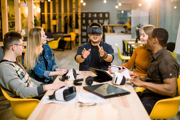 Grupp unga anställda anställda att ha kul med VR Virtual Reality Goggles i startup Studio. Ung kinesisk man bär VR glasögon. — Stockfoto