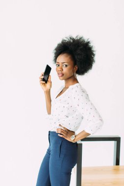 neşeli genç afro amerikan iş kadını cep telefonu konuşuyor, modern sandalyenin yanında duran, beyaz izole