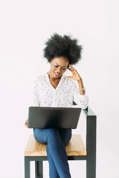 Allegra giovane donna d'affari afro-americana concentrata e confusa, usando il computer portatile, isolata sul bianco — Foto Stock