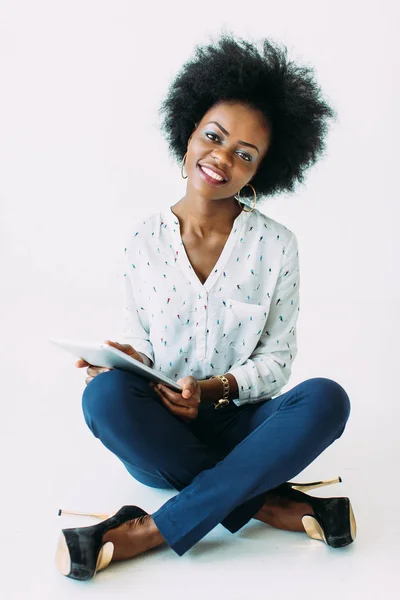 Jonge Afro-Amerikaanse zakenvrouw die de tablet gebruikt terwijl hij op de vloer zit, geïsoleerd op wit — Stockfoto