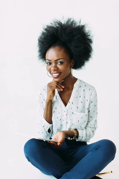 Jonge Afro-Amerikaanse zakenvrouw die de tablet gebruikt terwijl hij op de vloer zit, geïsoleerd op wit — Stockfoto