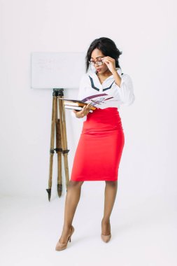 Beyaz gömlek ve kırmızı etek kitap ve belgeler tutan güzel genç afrikalı gülümseyen kadın öğretmen