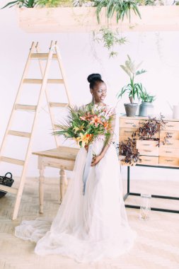 Stüdyoda tropikal buket ile güzel afrikalı amerikalı gelin