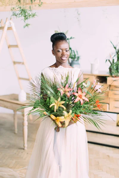 Bela noiva afro-americana com buquê tropical em estúdio — Fotografia de Stock