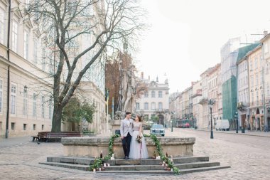 Sevgi dolu çift anıtın taş merdivenlerde açık havada ayakta ve kucaklayan. Bir sürü mum, çiçek, merdivenlerde romantik düğün dekoru. Eski şehirde düğün töreni
