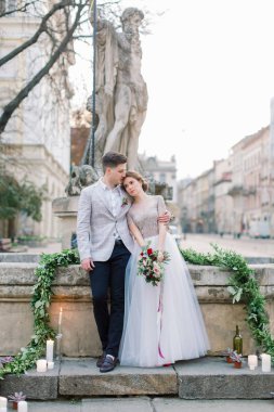 Düğün konsepti. Mutlu romantik düğün çift eski şehir binalarının önünde taş merdivenlerde duruyor. Romantik damat ve aşık gelin kucaklayan. Lviv, Ukrayna