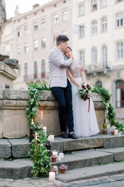 Svatební myšlenka. Šťastný romantický svatební pár stojí na kamenných schodech před starými městskými budovami. Zamilovaný Romantik a nevěsta s láskou. Lvov, Ukrajina — Stock fotografie