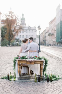 Romantik akşam yemeği mutlu düğün çift, dekore ahşap masada oturuyor. Arka planda inanılmaz eski Lviv mimarisi