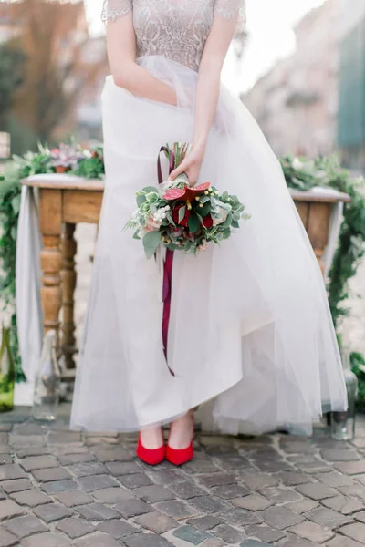 Güzel gelin, Eski Şehir merkezinde bir dekor ile ahşap masanın yanında duran, bir gelin buketi tutar