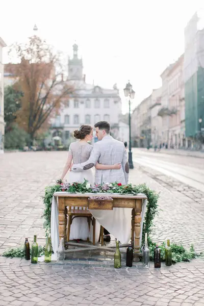 Romantik akşam yemeği mutlu düğün çift, dekore ahşap masada oturuyor. Arka planda inanılmaz eski Lviv mimarisi