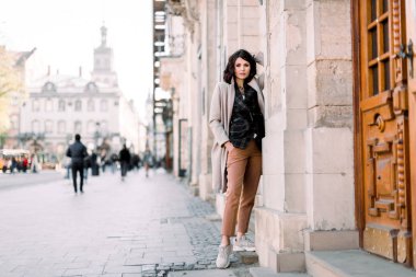 Eski şehir caddesinde poz, şık giysiler, ceket ve pantolon yüksek moda kadın model açık portre