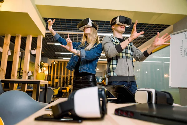 깜짝 놀랄 젊은 아름 다운 커플 테스트 가상 현실 3D 비디오 안경 VR 헤드셋 캐주얼 복장에 복장 호기심 에 의해 증강 현실 에 의해 현대 사무실 — 스톡 사진