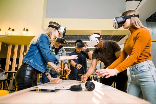 Affärsfolk som använder Virtual Reality Goggles under mötet. Team av multietniska utvecklare testa Virtual Reality headset och diskutera nya idéer för att förbättra den visuella upplevelsen. — Stockfoto