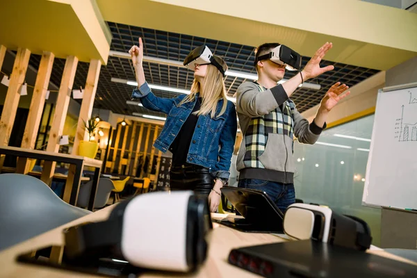Jeune homme et femme souriants en lunettes VR regardant les mains excitées par la réalité augmentée. Couple essayer vr lunettes et avoir du plaisir à l'intérieur — Photo