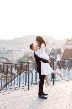 Eski şehrin terasında yürüyüş genç güzel Asyalı çift. Arka planda panoramik şehir manzarası. Kadını elleri tutan adam