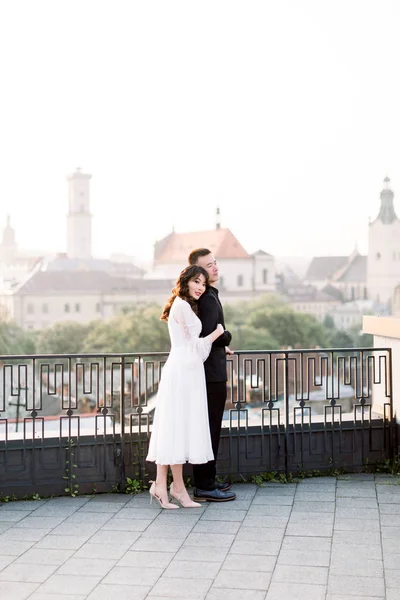 Kinesiska brudgummen stilig man och vacker brud ung söt kvinna i vit brudklänning, Asiatiska par stående utomhus på City Terrace, panoramautsikt över gamla stan — Stockfoto