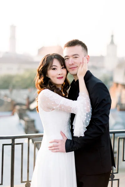 Jeune belle mariée asiatique et marié, couple heureux au coucher du soleil dans la vieille ville européenne. Histoire d'amour de mariage en Europe . — Photo