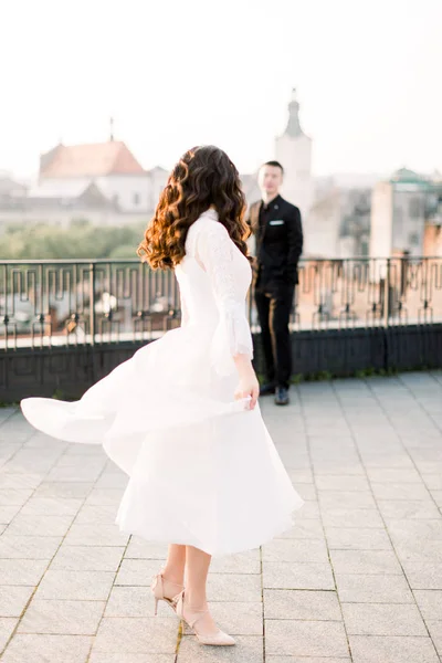 Молода красива Азіатська наречена в білому весільній сукні танцює на терасі стародавнього міста. Наречений стояв на задньому плані. Весільна Прогулянка в Старому місті — стокове фото