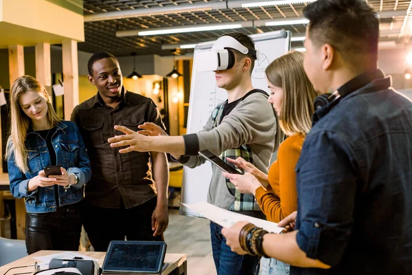 Équipe d'affaires de jeunes gens multiethniques présentant un nouveau projet à un client sur un simulateur de réalité virtuelle. Jeune homme caucasien le client avec des lunettes VR . — Photo