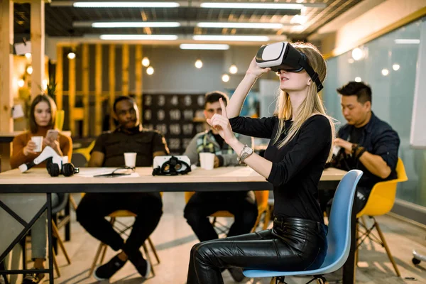 Business team av multietniska människor som arbetar med virtuell verklighet applikationer och spel, unga upphetsad kvinna testa VR glasögon eller glasögon sitter i kontorsrum med medarbetare — Stockfoto