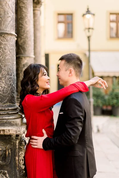 Young beautiful Chinese couple in love hugging each other on old city street, summer Europe vacation, travel, fun, happy, smiling, date, embracing — Stock Photo, Image