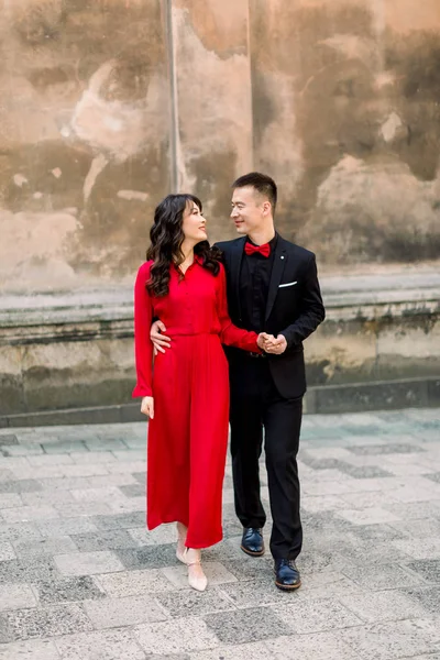 Pasangan pengantin wanita dan pria Asia yang bahagia dan cantik di latar belakang kota tua. Wanita bergaun merah dan pria berjas hitam — Stok Foto