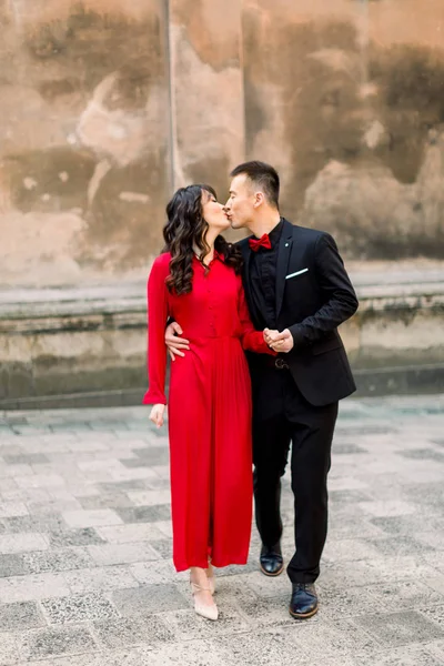 Joyeux et charmant couple asiatique de mariés dans le contexte de la vieille ville. Femme en robe rouge et homme en costume noir — Photo