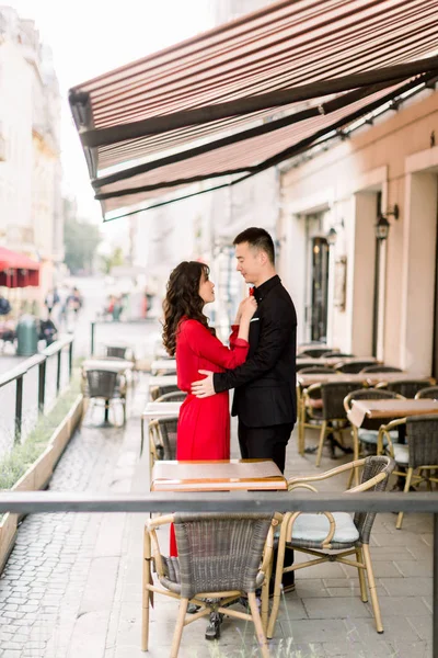 Feliz de estar juntos. Atractiva pareja china en ropa elegante posando en la cafetería de paseo lateral en el centro de la ciudad vieja . — Foto de Stock