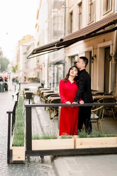 Feliz de estar juntos. Atractiva pareja china en ropa elegante posando en la cafetería de paseo lateral en el centro de la ciudad vieja . —  Fotos de Stock