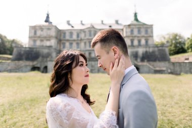 Close-up portrait of charming and fashionable Chinese wedding couple in love, standing on the background of old vintage castle