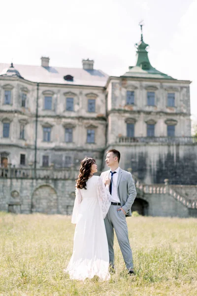 Щаслива весільна пара стоїть і ходить біля старого стародавнього замку — стокове фото