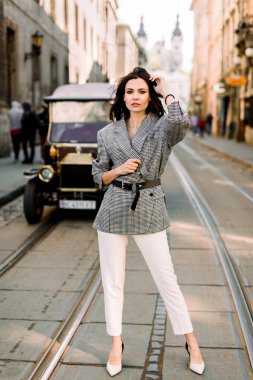 Şehir caddesinde duran çekici modern kadın. Bir şehir sokakta güzel zarif kadın, arka planda retro araba