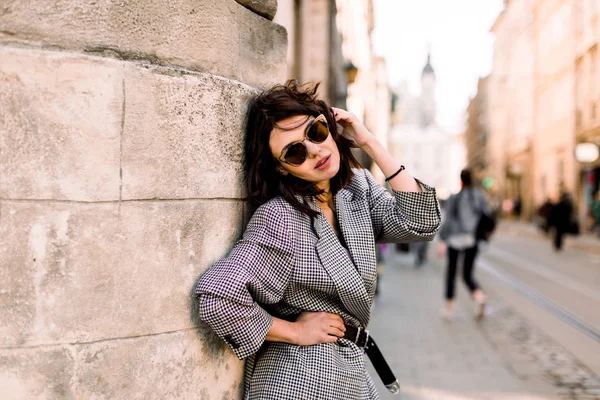 Щаслива кавказька жінка в літні сонячні окуляри посміхаються під час постановки на відкритому повітрі в місті в сонячний день, жіноча особа, стоячи зі складом копіювати простір на стороні — стокове фото