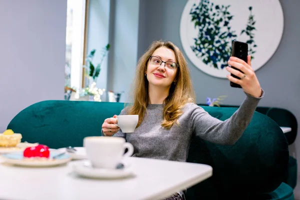 Технологія і люди концептуальні - щаслива кавказька жінка з тортом і кавою, що селекціонує за допомогою смартфона в кафе. — стокове фото