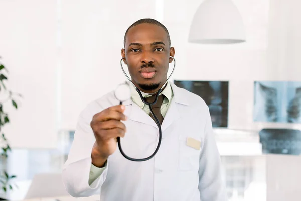 friendly african american doctor in modern office. Portrait of an handsome African man doctor, holding stethoscope