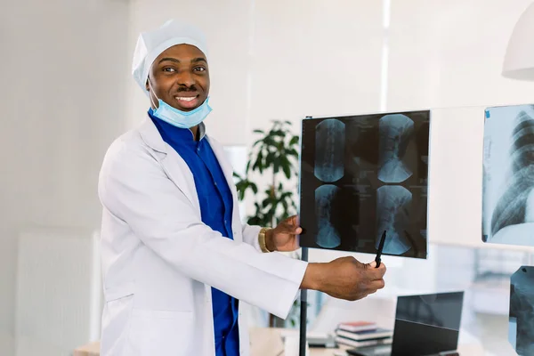 Cabinet médical et concept de pratique médicale. Médecin afro-américain souriant professionnel à la clinique pointant sur la radiographie . — Photo