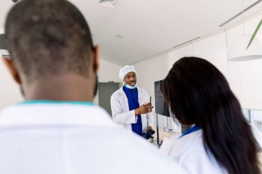 Röntgenli doktor ekibi. Sağlık hizmetleri. Radyoloji. Uzman doktorlar ekibi hastanede röntgen raporunu inceliyor. Tahtanın yanında duran Afrikalı doktor.