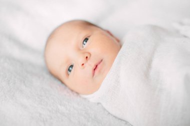 Beyaz saç bandı takmış, kürklü kumaşın üzerinde yatan tatlı yeni doğmuş kız.