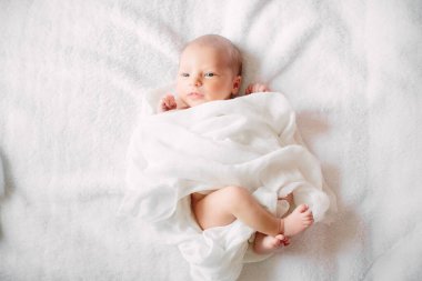Beyaz saç bandı takmış, kürklü kumaş üzerinde uyuyan yeni doğmuş tatlı bir kız.