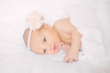 Beyaz saç bandı takmış, kürklü kumaş üzerinde uyuyan yeni doğmuş tatlı bir kız.