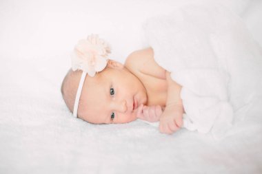 Beyaz saç bandı takmış, kürklü kumaş üzerinde uyuyan yeni doğmuş tatlı bir kız.